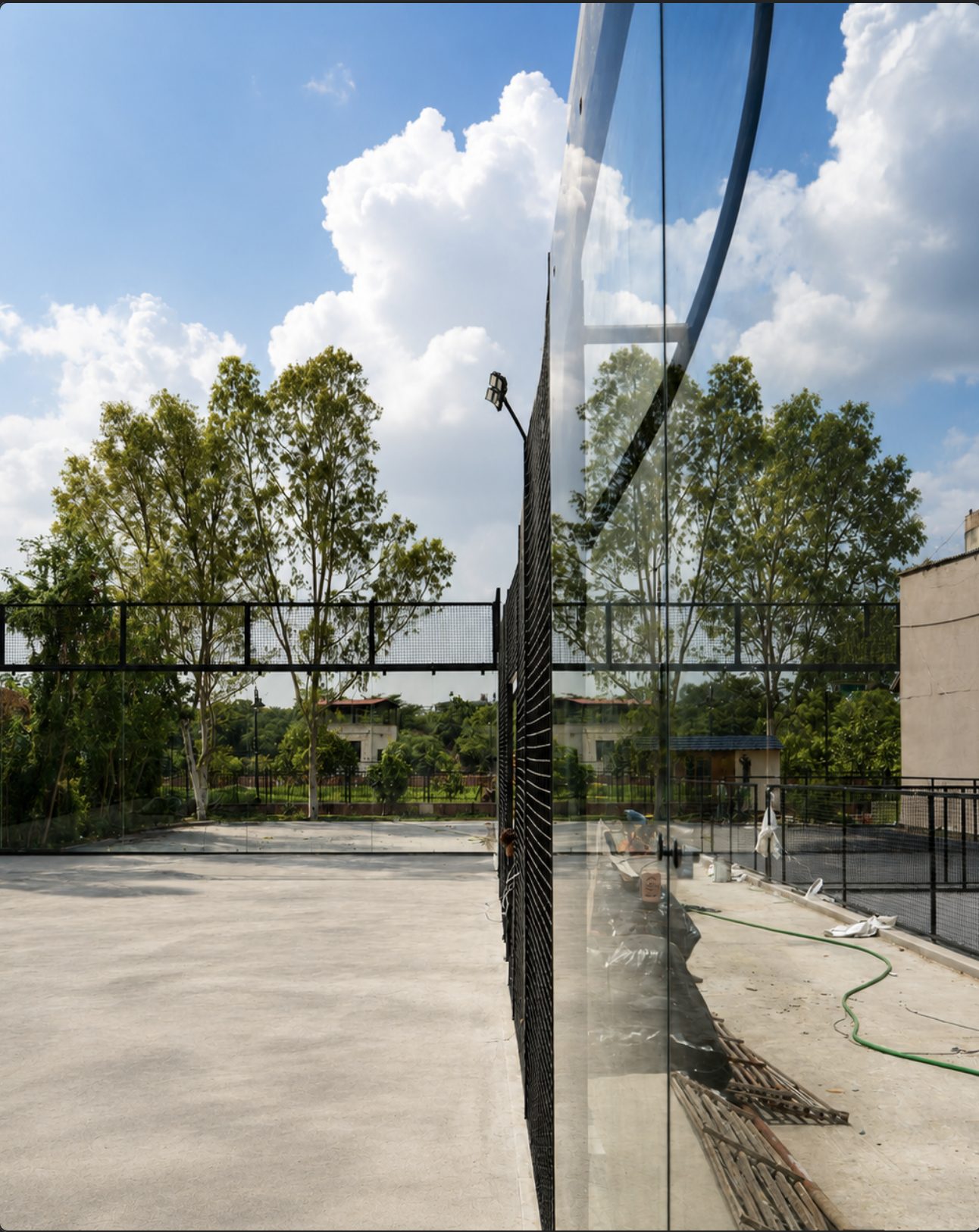 Padel court glass wall reflecting the Jaipur sky
